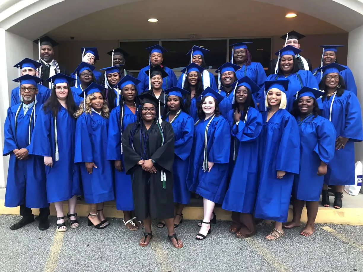 2022 Graduates of Helms College standing outside the campus main door.