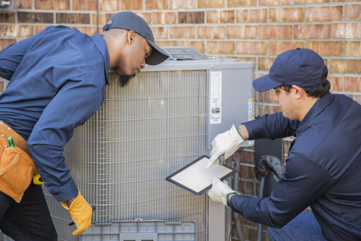 Multi-ethnic team of air conditioner repairmen at work