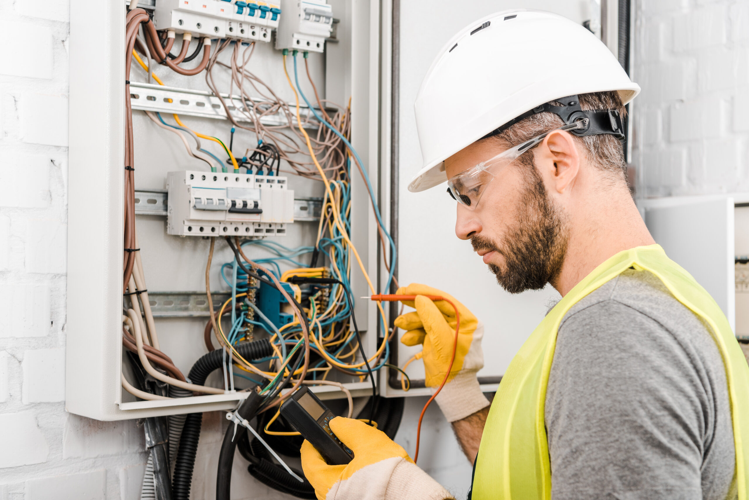 electrician checking electrical box with multimeter in corridor