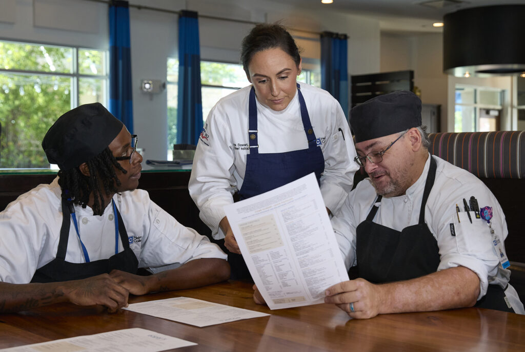 A group of culinary chefs review a menu together.