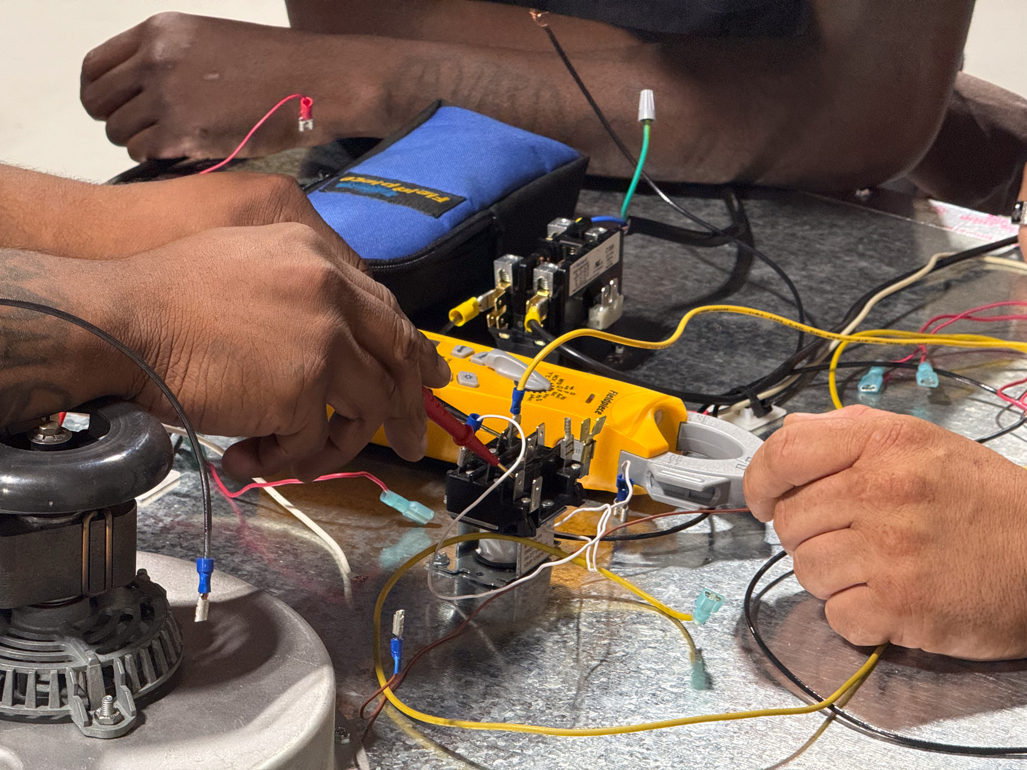 Hands work on electrical wires.